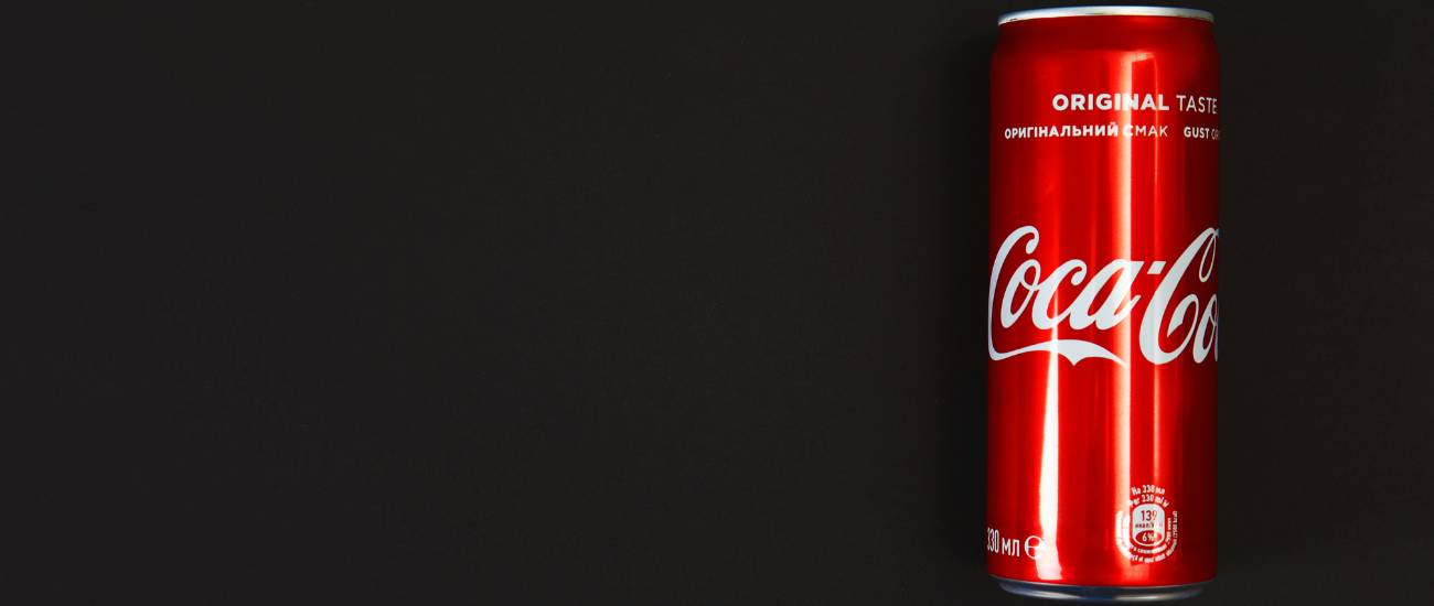 یک قوطی فلزی نوشابه کوکاکولا به رنگ قرمز در پس زمینه تیره و در سمت راست تصویر قرار دارد.